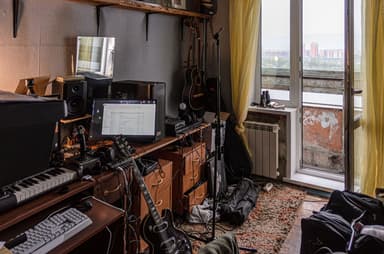 Home music studio with desk, keyboards, guitars, and audio equipment
