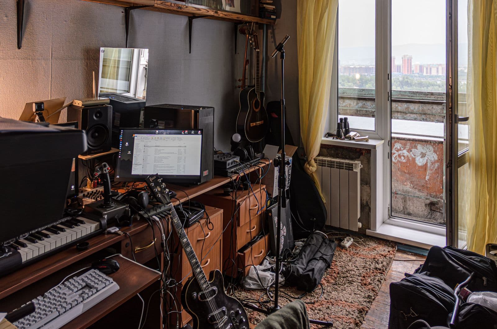 Home music studio with desk, keyboards, guitars, and audio equipment