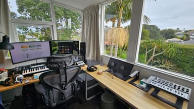 Auckland home studio with desk, monitors, MIDI keyboard, and greenery outside