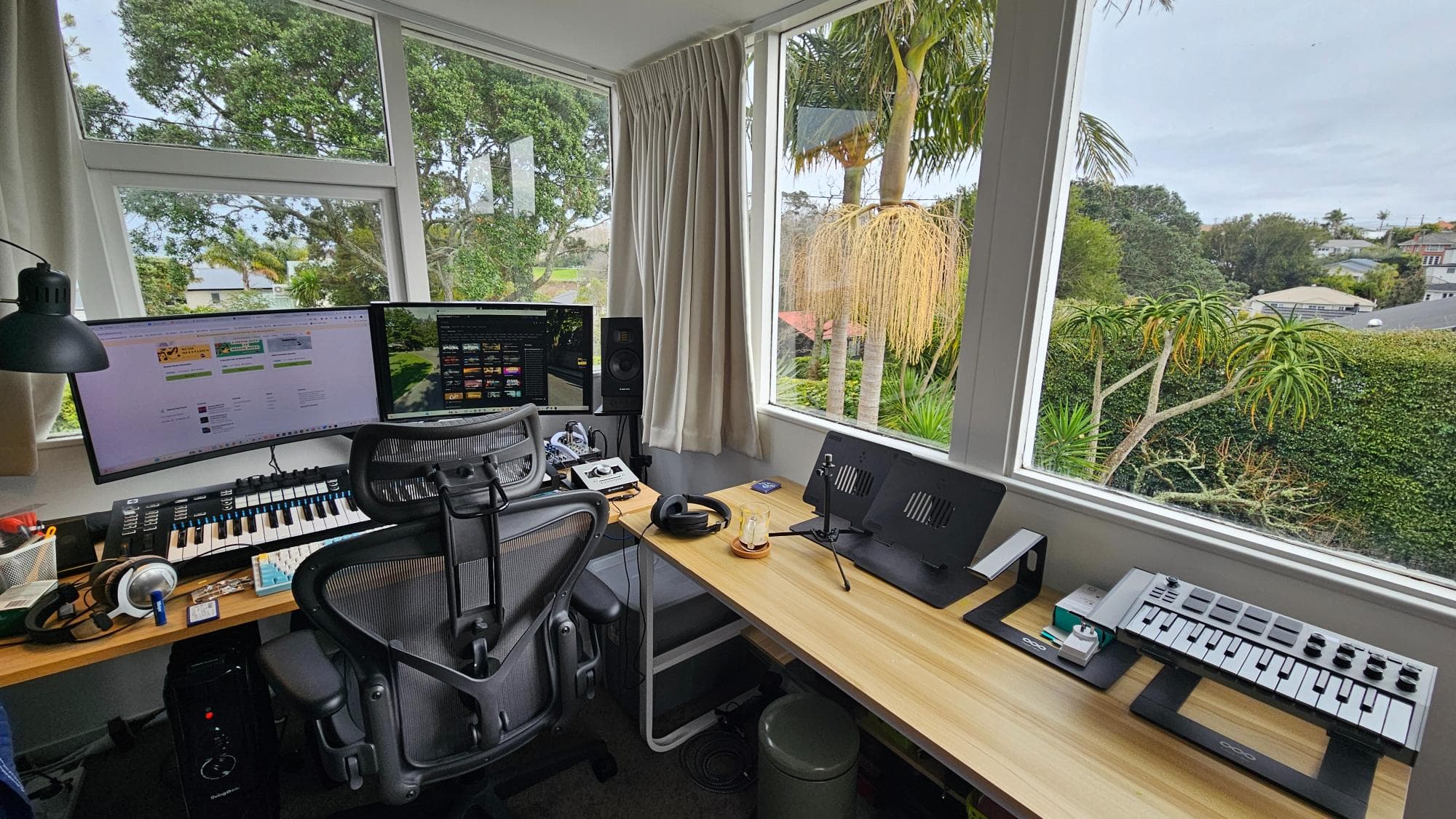 Auckland home studio with desk, monitors, MIDI keyboard, and greenery outside