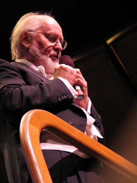 John Williams in a tuxedo, holding a microphone